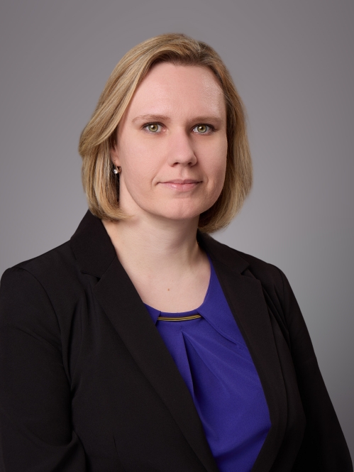 Headshot of female with shoulder length light brown hair wearing a blue blouse under a black jacket.