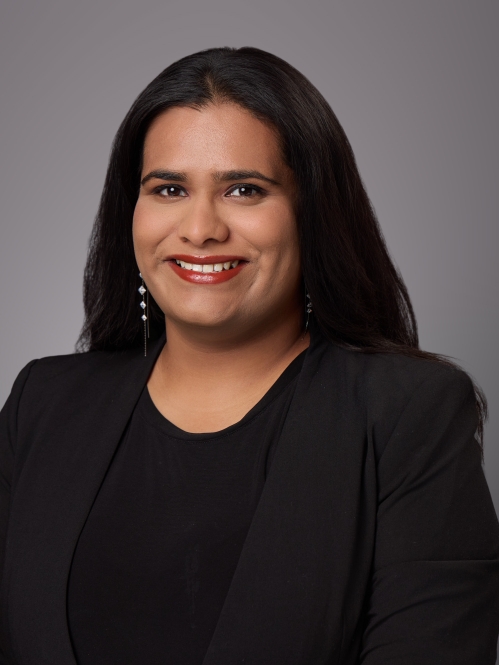 Headshot of female with long black hair wearing a black blouse under a black jacket.