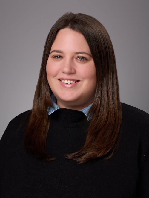 Headshot of female with long dark brown hair, wearing a black pullover.