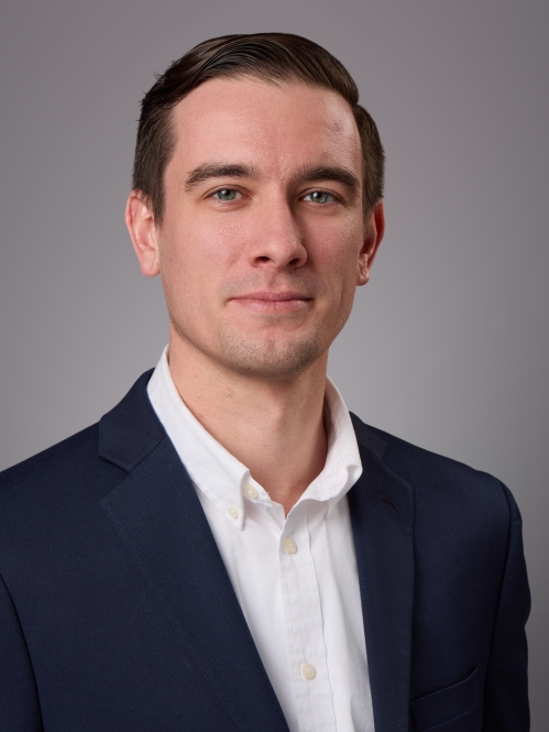 Headshot of male with short hair, wearing a whtie button down shirt and a black suit jacket.