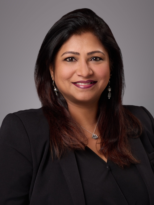 Headshot of woman with dark long hair wearing a black blouse underneath a black jacket.