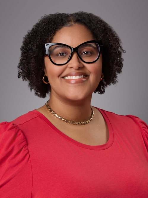 Headshot of black female with short curly hair and eyeglasses wearing a red blouse with a necklace.