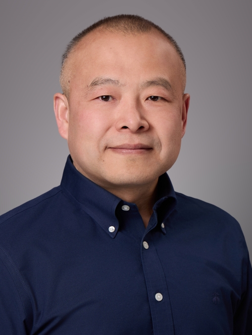 Headshot of male with very short hair wearing a blue button down shirt.