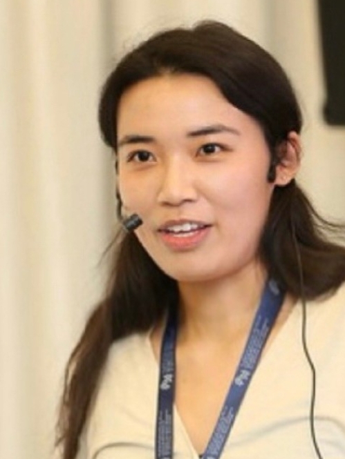 Headshot of woman with long black hair and light colored blouse.
