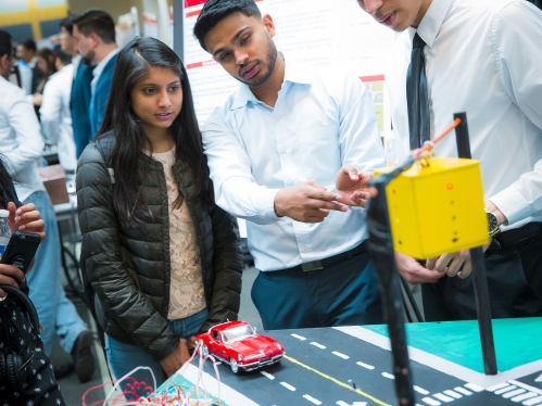 Two male students explaining a project to another student.