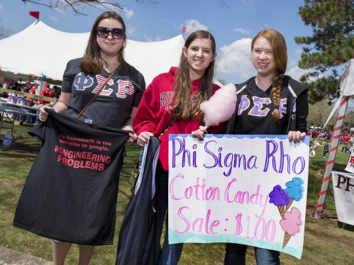 three female students holding poster and engineering shirt