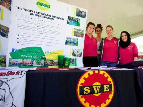 four young female students standing next to Society of Weomen Engineers poster