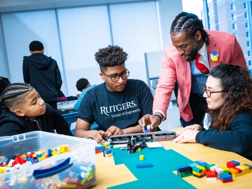 One black male instructor and one female white teacher instructing two young black male students.