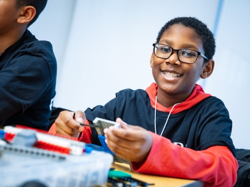 Smiling young black male with braces wearing glasses.