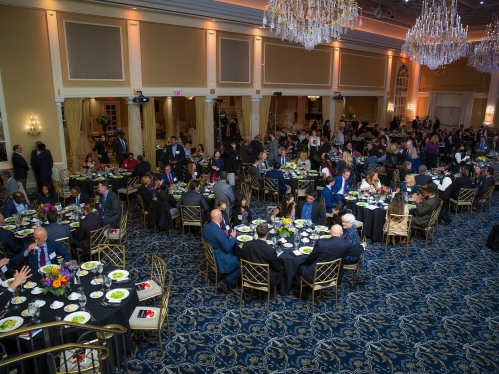 people seated around round tables preparing for dinner and award presentation ellence dinner