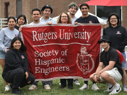 Students and their advisor holding up the Society of Hispanic Engineers banner