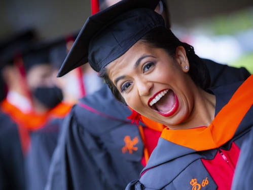 Happy, smiling female wearing regalia at graduation ceremony.