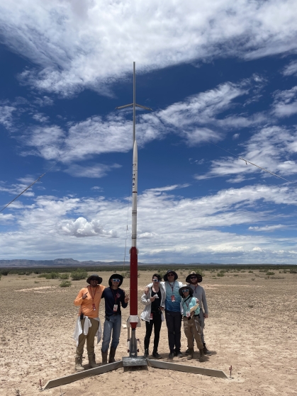 Six students standing with rocket