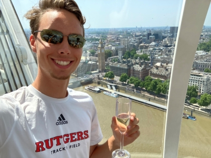 Young man in sunglasses holding a glass of champagne and wearing a Rutgers T-shirt photographed in the London Eye ferris wheel.