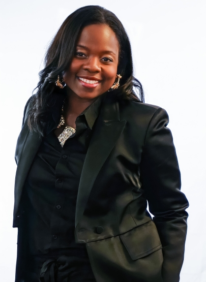 African-American woman in black blouse and jacket smiles in portrait