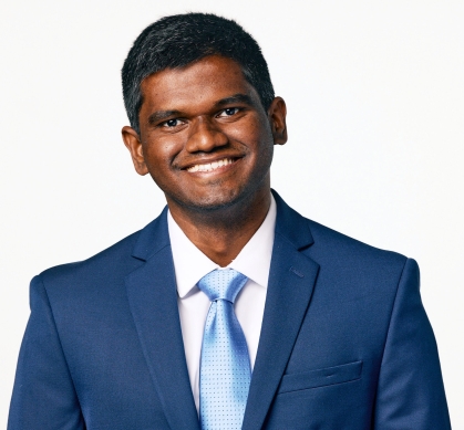 Headshot of South Asian male graduate student wearing a blue suit, light blue tie and white shirt. He is smiling and has short dark hair.