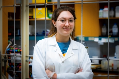 female student wearing eyeglasses with arms crossed wearing a white lab coat