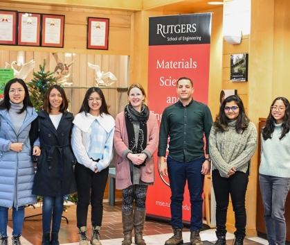 Six students standing side-by-side with their female professor.