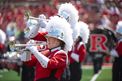 Marching band in red and black uniforms, close up of woman playing the trumpet.