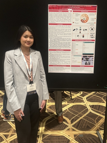 Young Asian female student standing next to her poster at a conference.