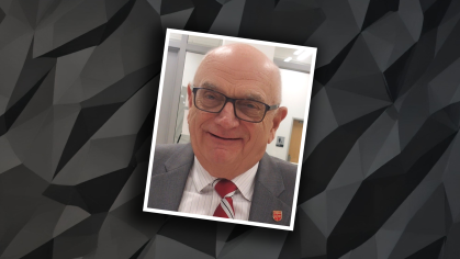 Headshot of balding male wearing eyeglasses against a balck graphic background.