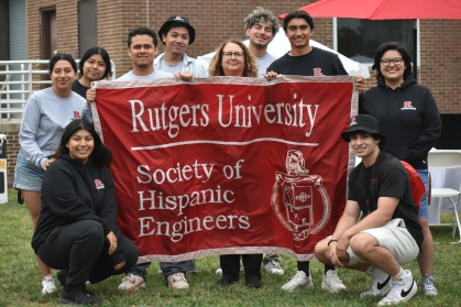 Students and their advisor holding up the Society of Hispanic Engineers banner