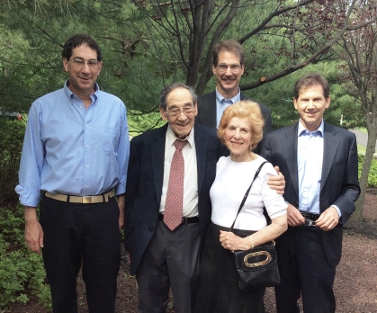 Family photo of five adult sons posing outside around an elderly man and woman.