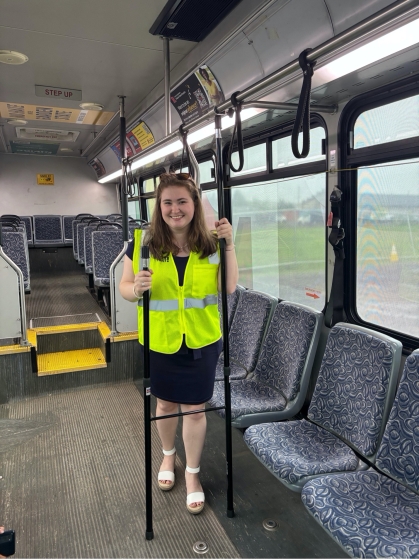 Student wearing a yellow safety vest, standing on a bus.
