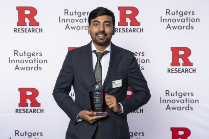 Male student wearing a suit holds an award. 
