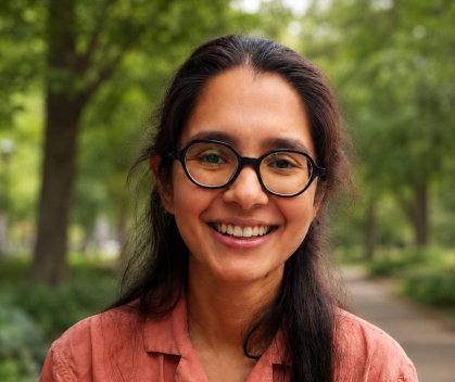 Woman with long dark hair and glasses standing outside
