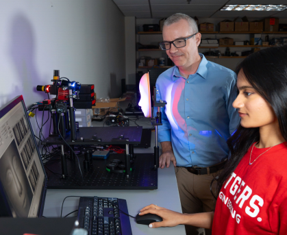 Faculty member standing next to student working on computer2