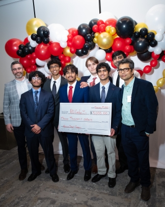 Group of students holding a large check flanked by two male judges.