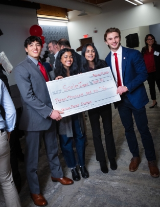 Two female and two male students holding a giant check.