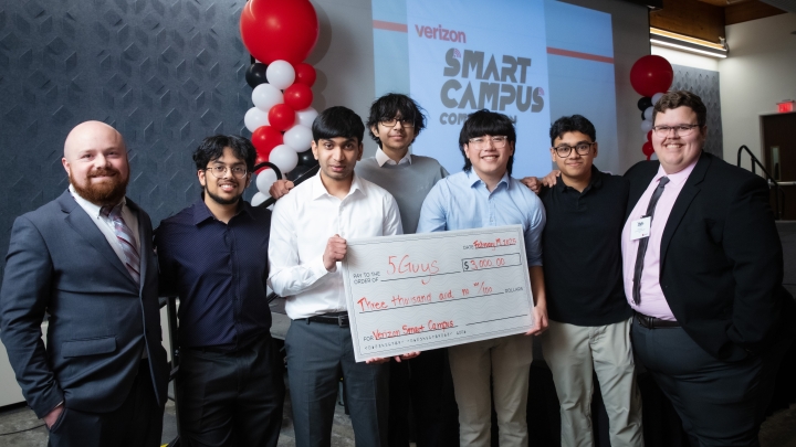 Group of seven males standing in front of Verizon Smart Campus logo