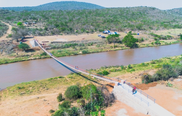 Big-picture view of the bridge and river, with surrounding land, greenery, and hills in view