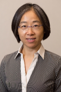 Head shot of Asian woman with short hair and eyeglasses, wearing a grey sweater and button down shirt.