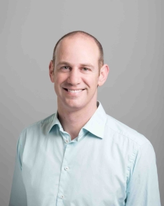 Head shot of male, Josh Taylor, wearing alight blue button down shirt.
