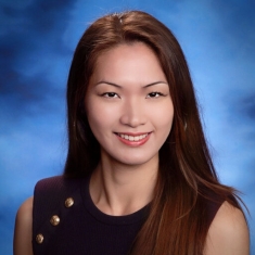 Headshot of female with long black, straight hair wearing a dark purple dress with gold buttons.