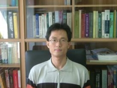Headshot of male seated in front of a bookcase wearing eyeglasses and a polo shirt.